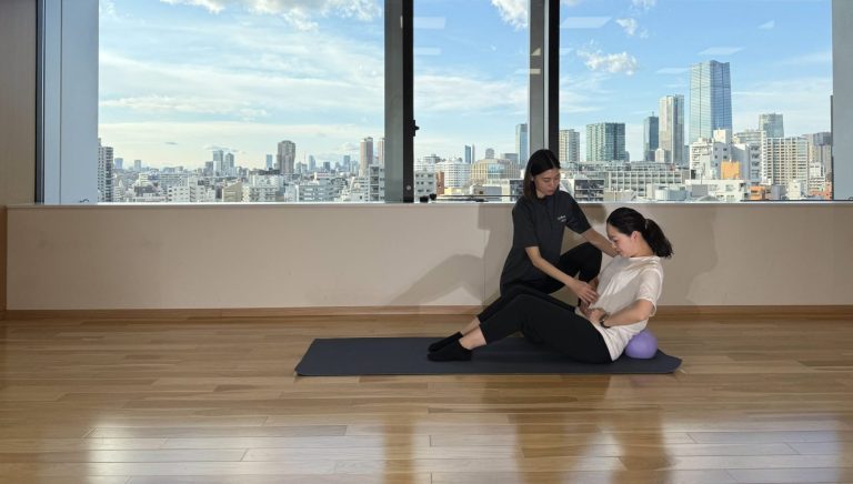 スタッフがマット上で個別のストレッチを支援する様子